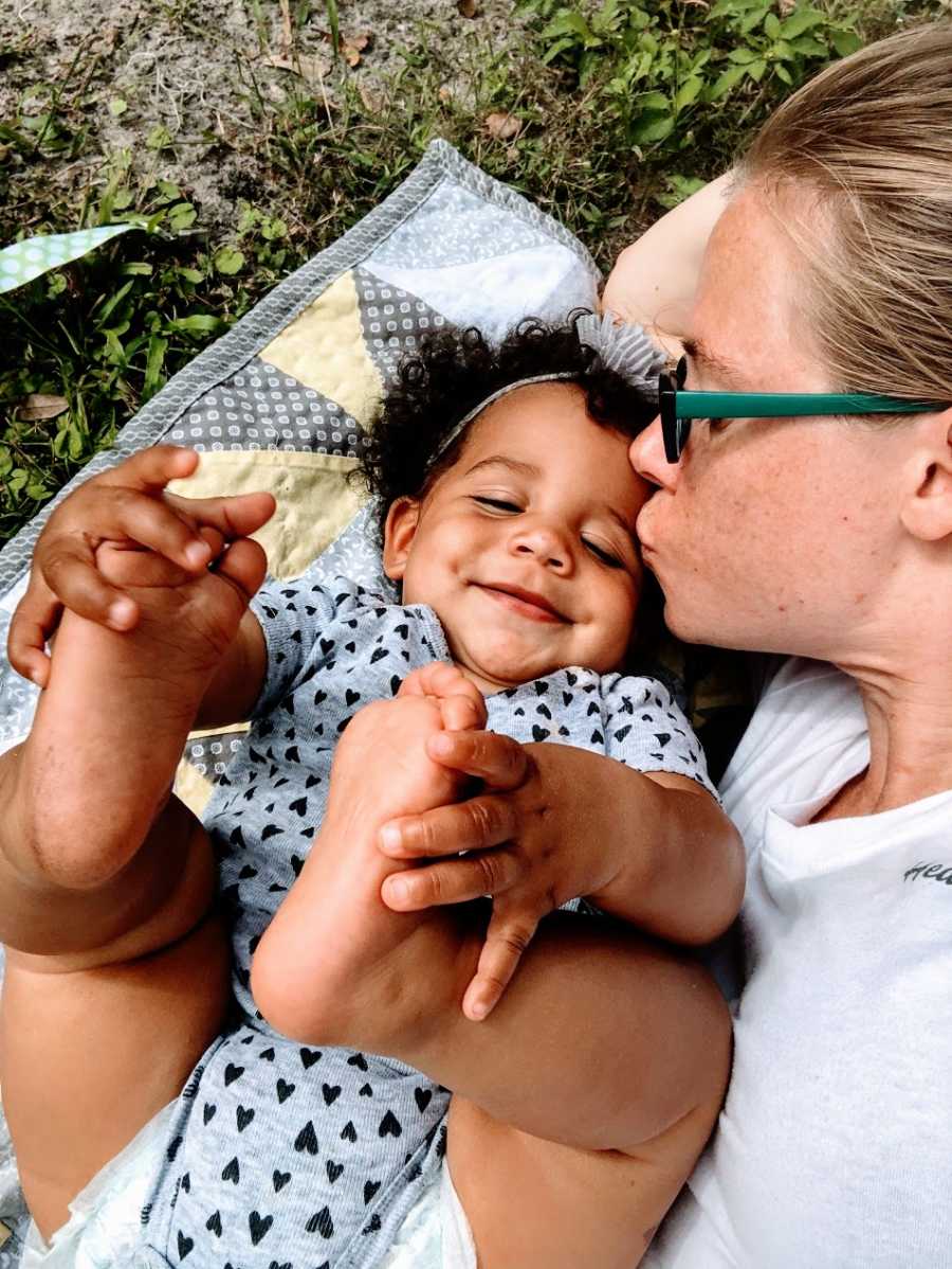 A mother kisses her baby girl on the forehead