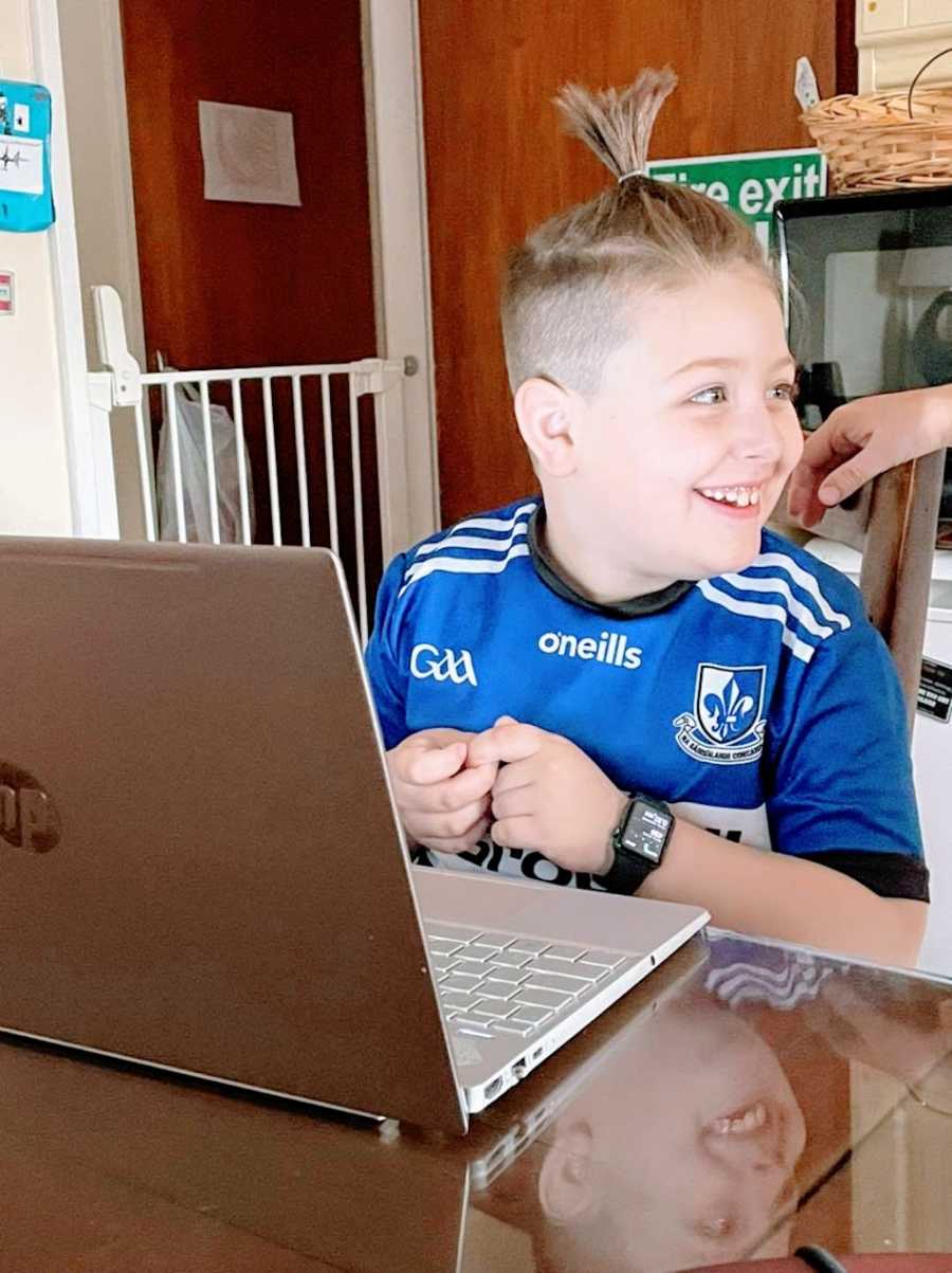 Am Autistic boy wearing a blue shirt sits at a computer