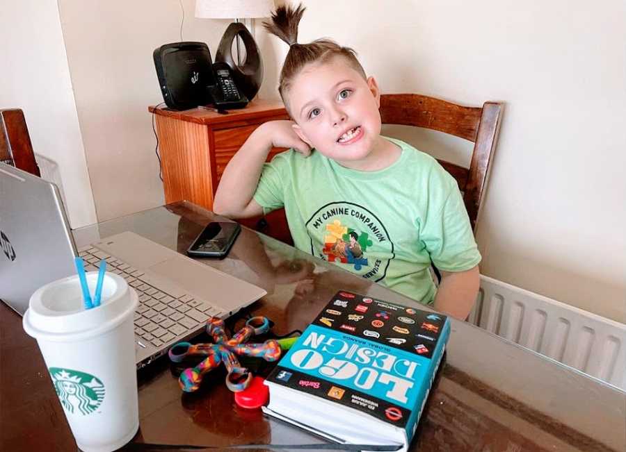 An Autistic boy in a green shirt sits at a table