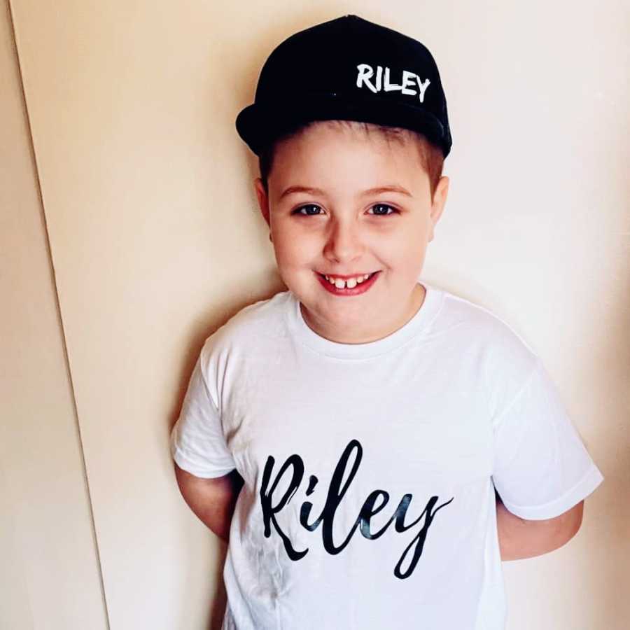 A boy wearing a black hat and a white shirt with his name on them