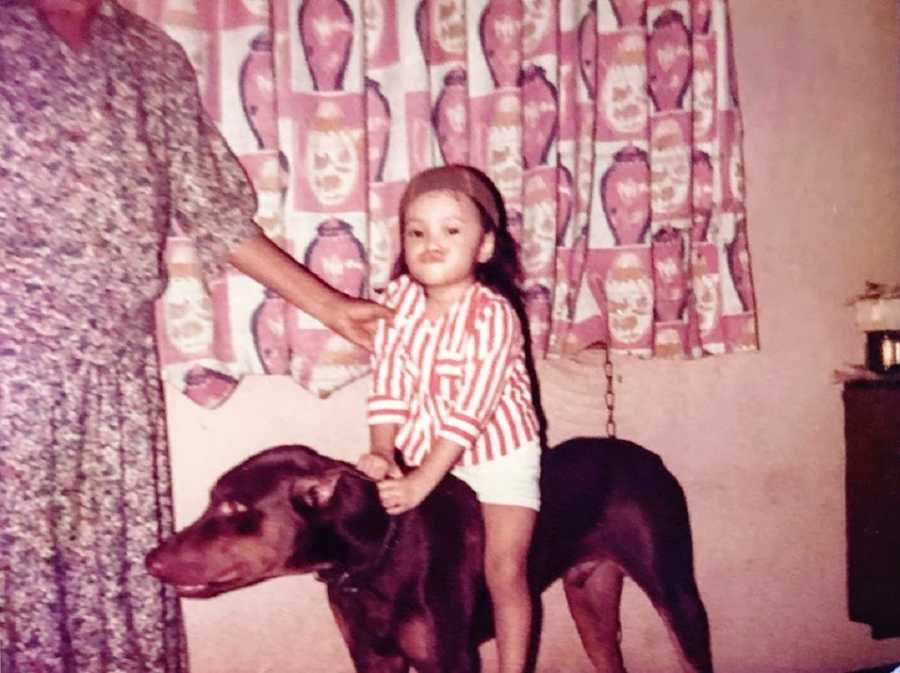 A little girl sits on a big dog like a horse