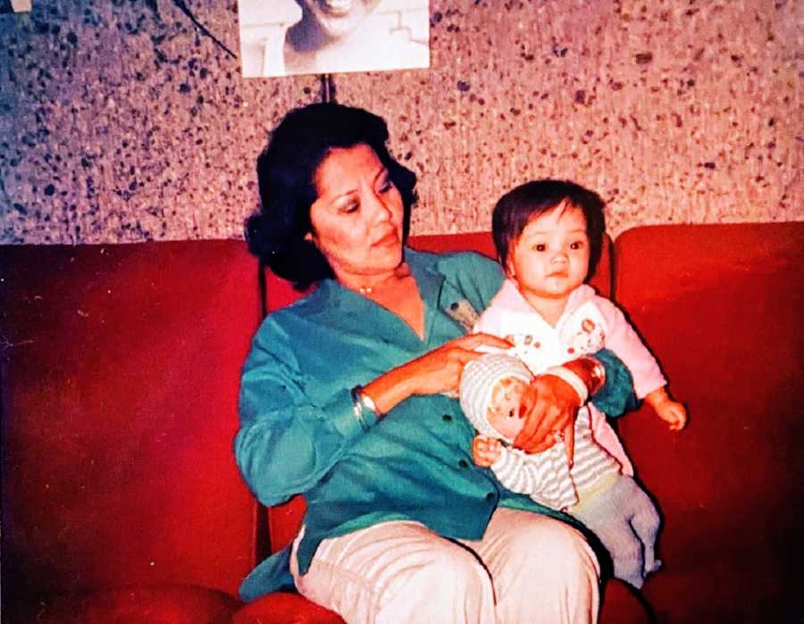 A woman holds her adoptive daughter on a couch