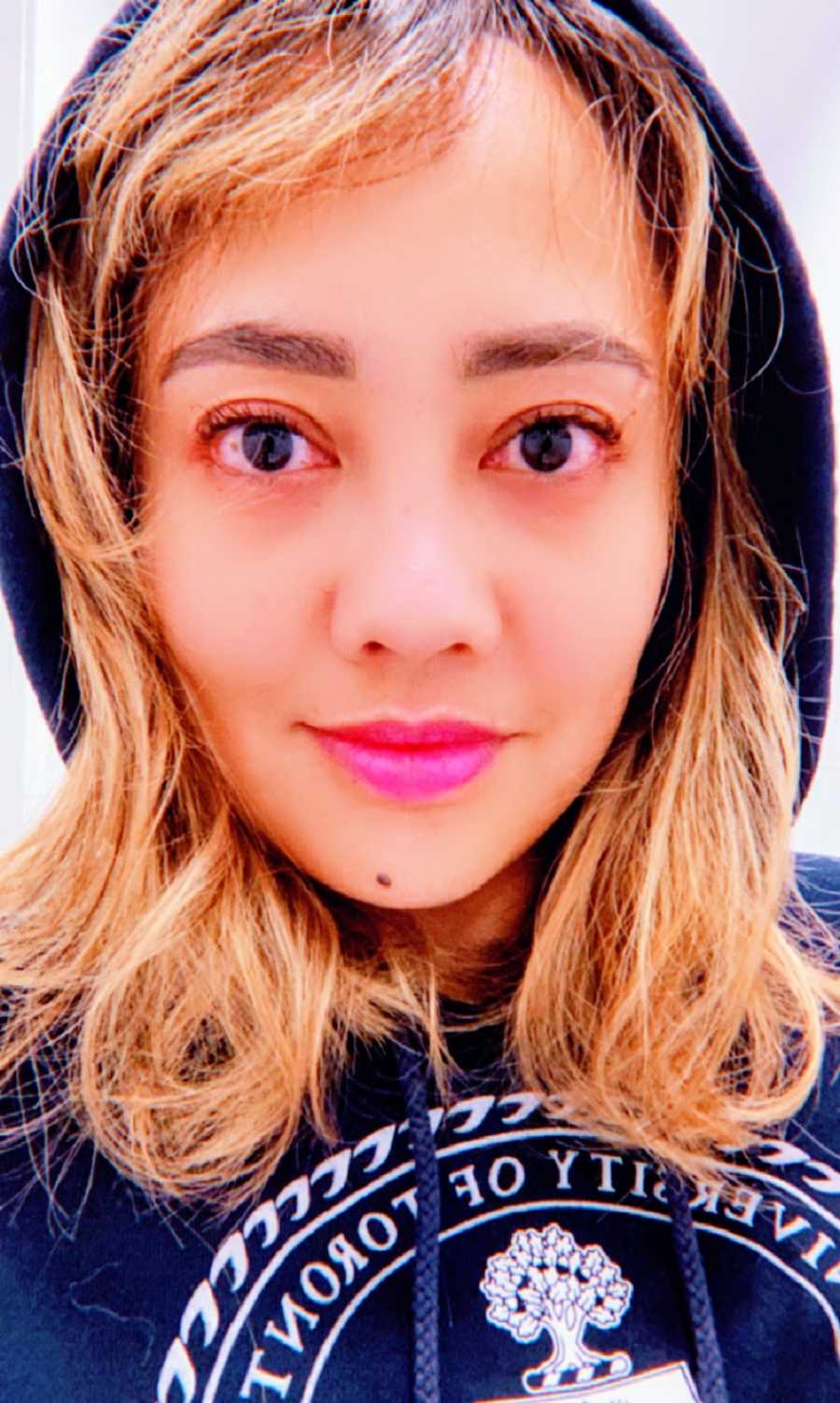 A woman wearing a hoodie and pink lipstick
