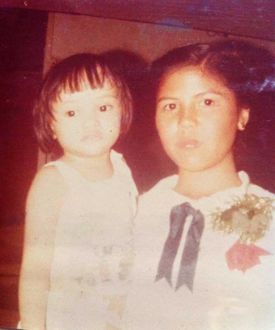 A little girl sits with her older sister who is really her birth mom