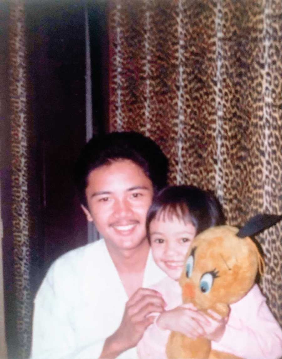 A little girl holding a stuffed animal sits with a young man