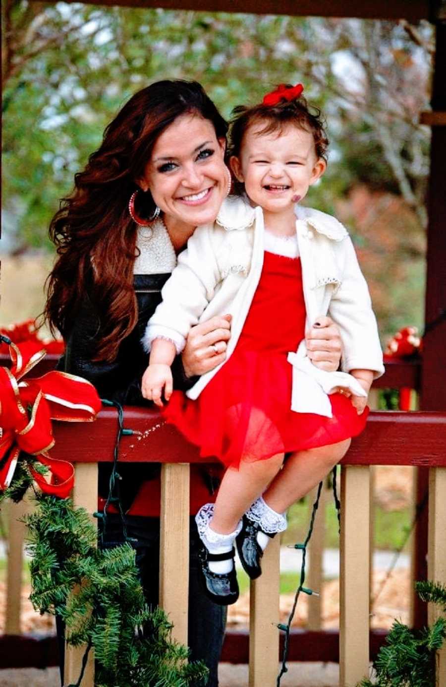 Mom holds young daughter dressed for Christmas