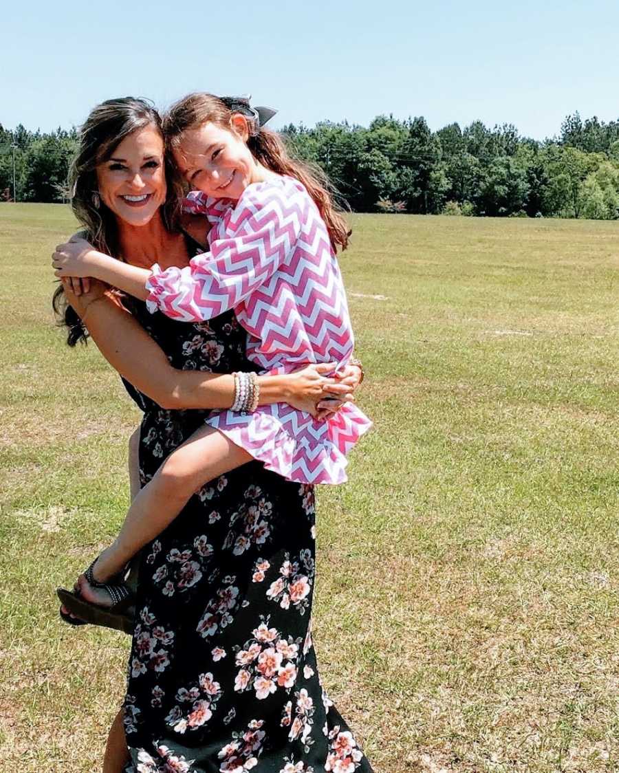 Young mother holds daughter up outside