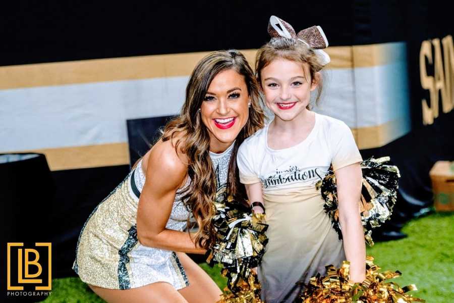 Mom and daughter in cheerleading outfits at football game