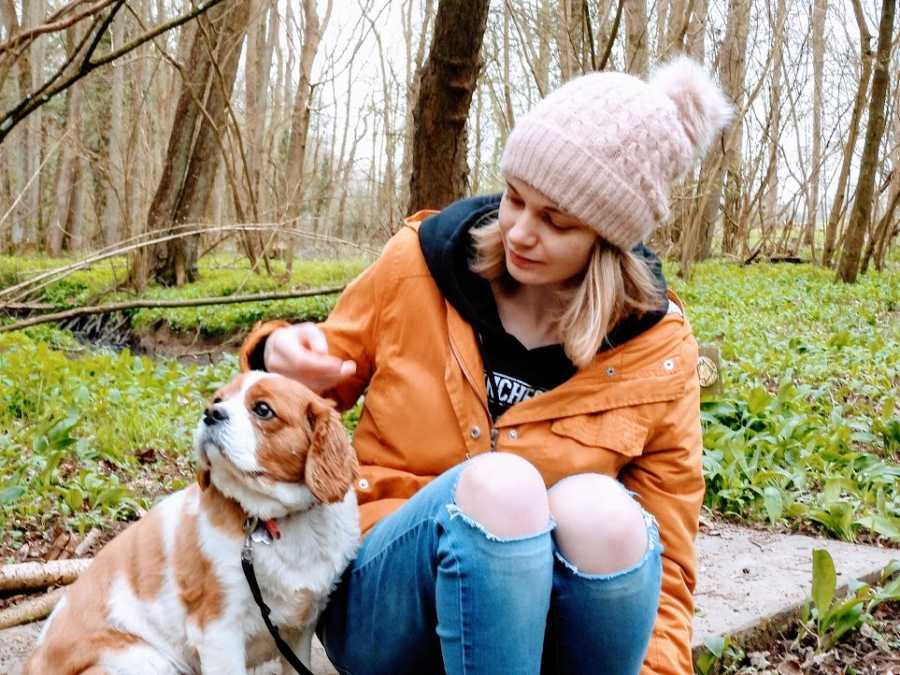 Woman sits with small dog outside