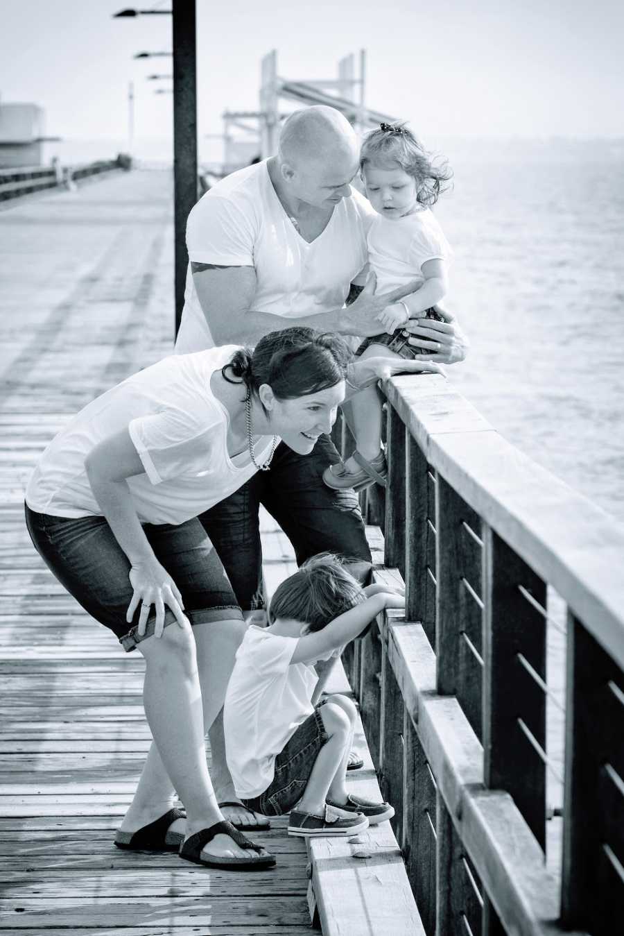 Parents with their two young children on a bridge by the water