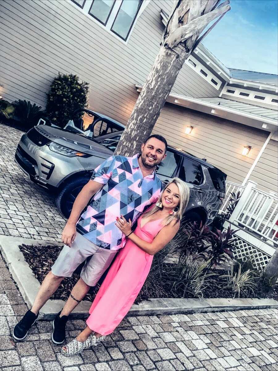 Couple experiencing unexplained infertility take a photo before date night in their front yard while wearing color-coordinated outfits