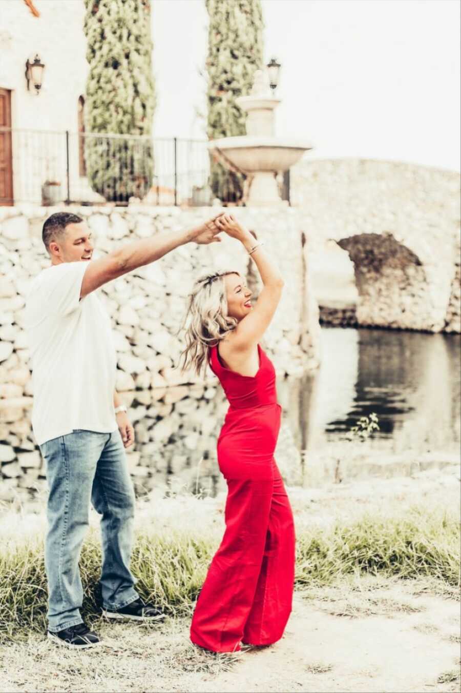 Young couple dance together while taking photos announcing their embryo adoption