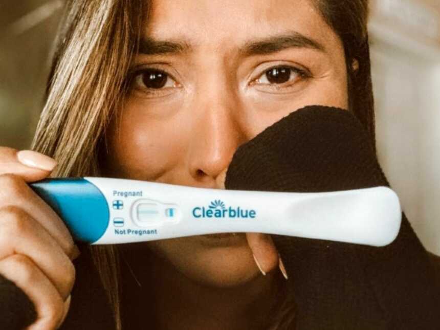 Woman holds up a negative pregnancy test while crying