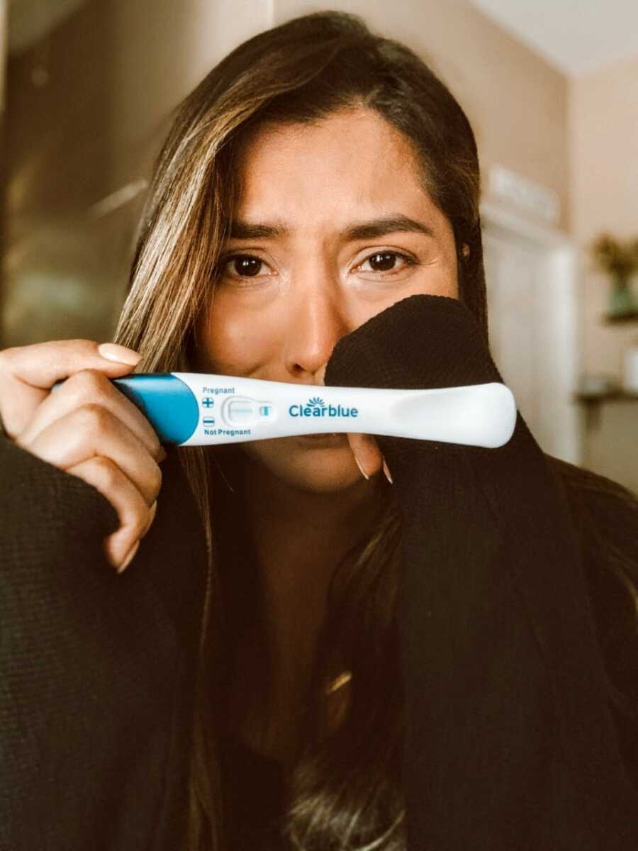 Woman trying to conceive cries while she takes a photo with a negative pregnancy test