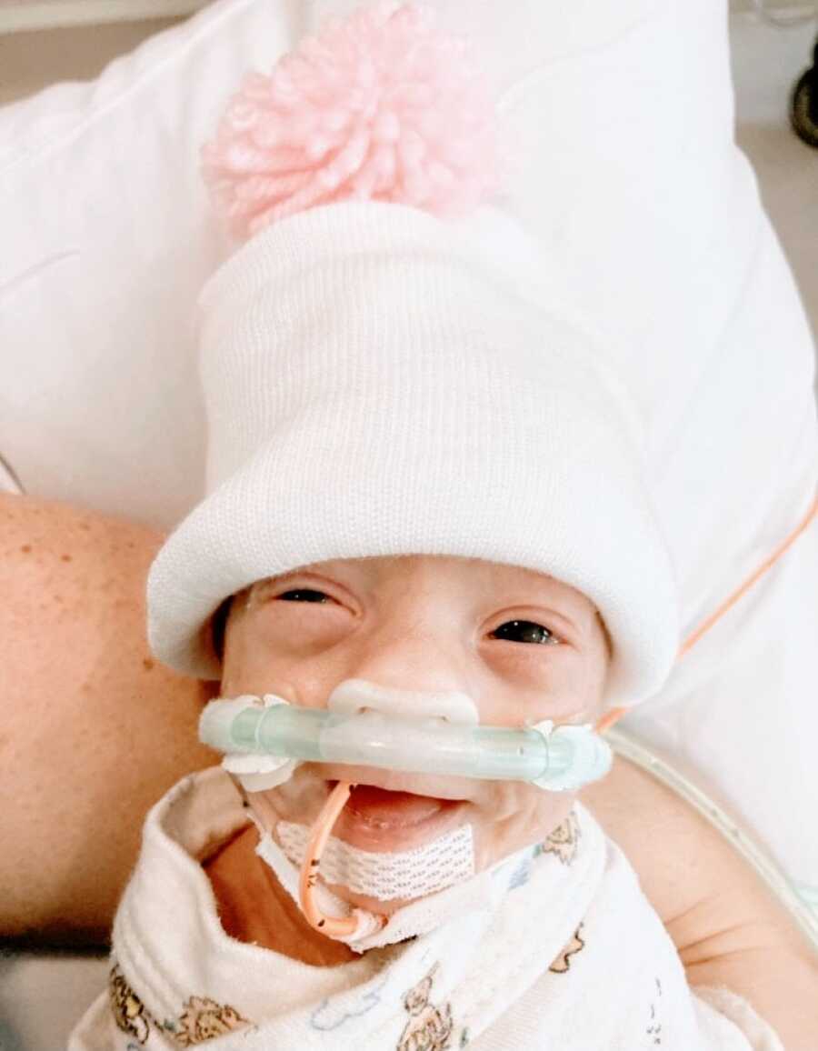 Mom snaps photo of one of her newborn preemie twins wearing a beanie with a pink pompom on it