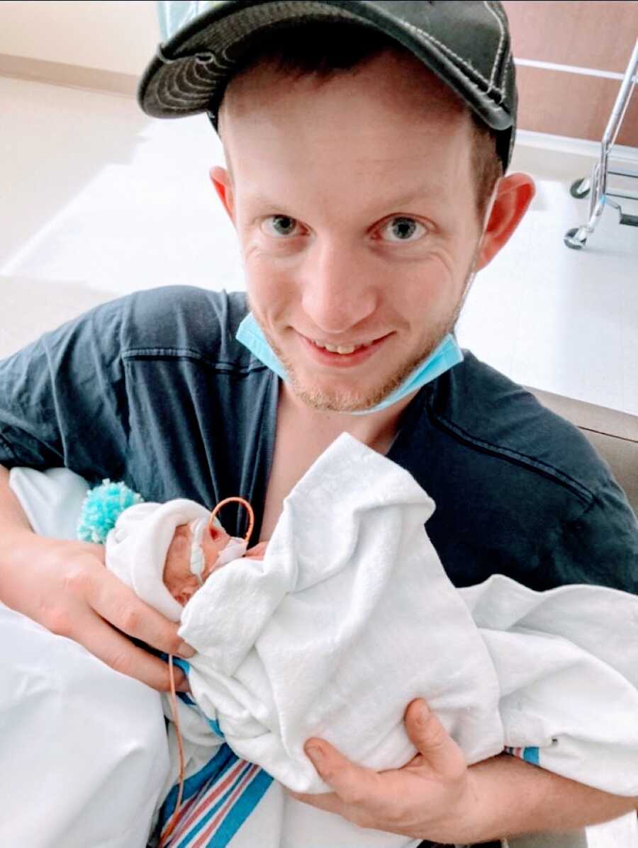 Dad holds one of his twin daughters for the first time, 12 days after birth via and emergency C-section