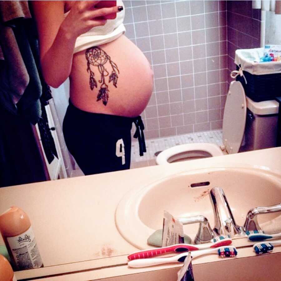 Pregnant teen takes a photo of her growing baby bump in the bathroom