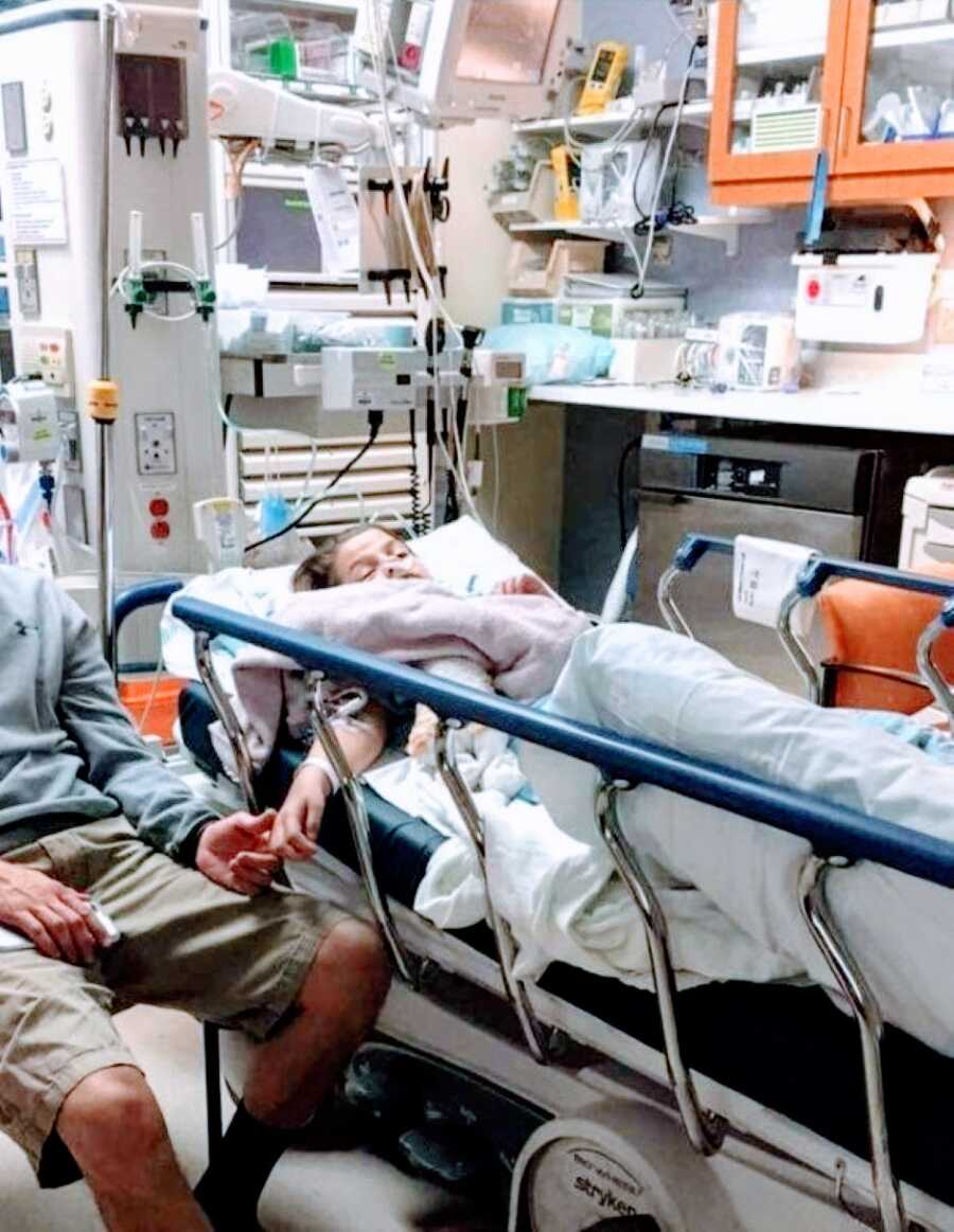 Little girl suffering from a spinal stroke holds her dads hand while waiting results in the hospital