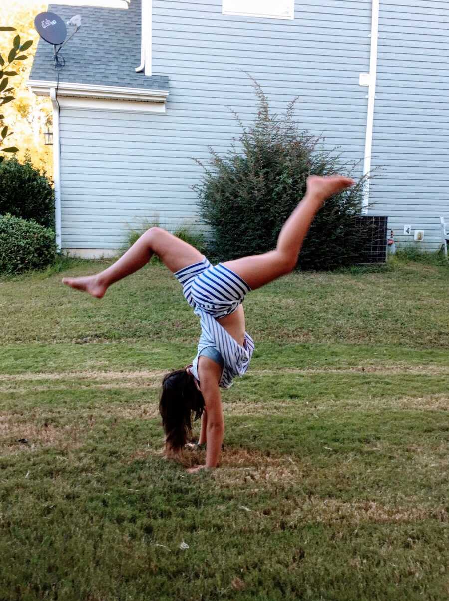 Preteen daughter practices gymnastics in her backyard