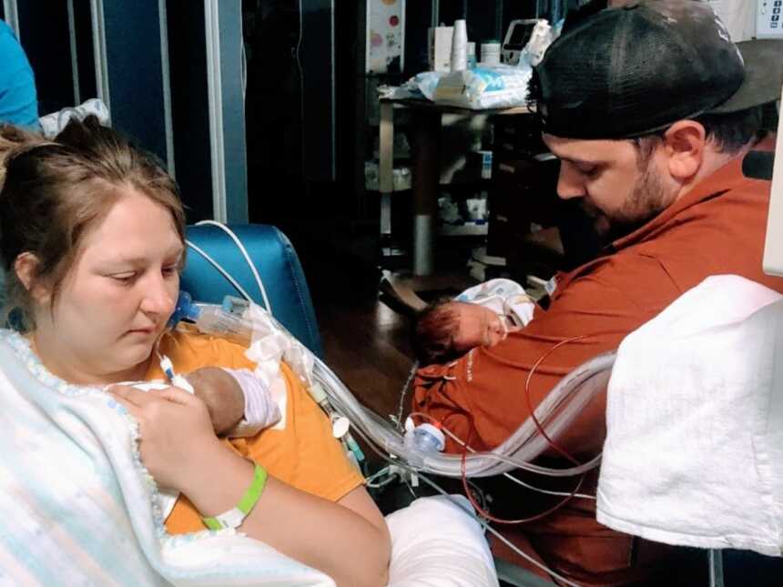 新生儿父母在新生儿重症监护室里抱着他们早产的双胞胎