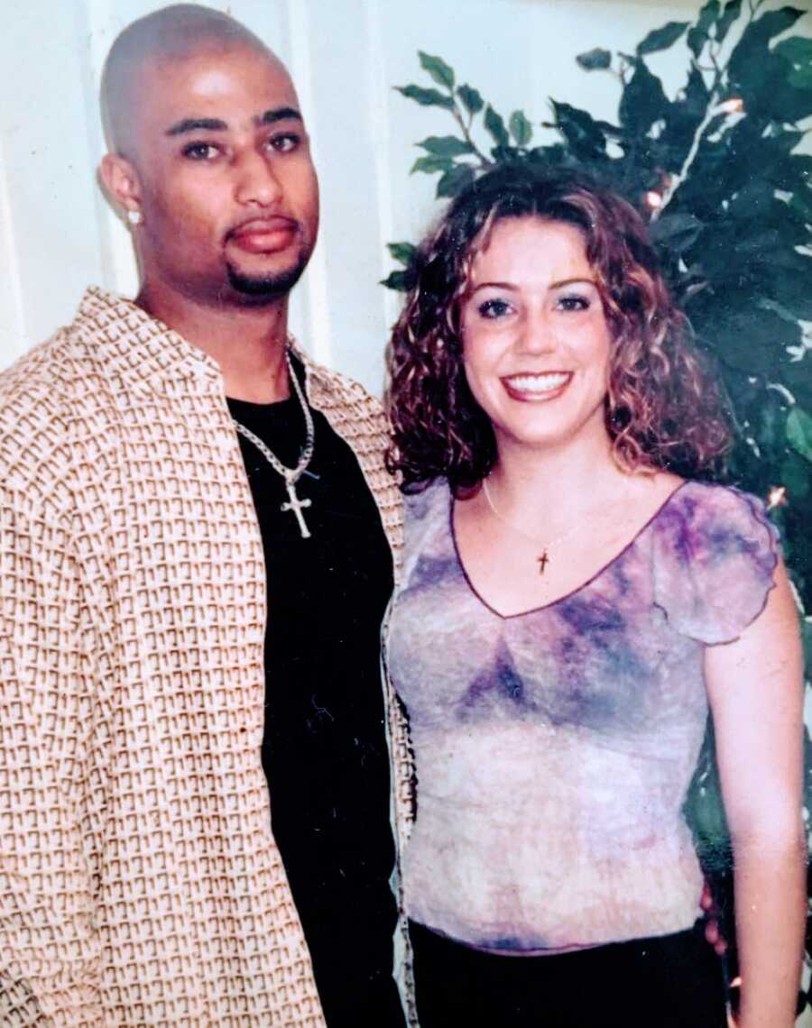 Young interracial couple smile for a photo together in very 90s outfits