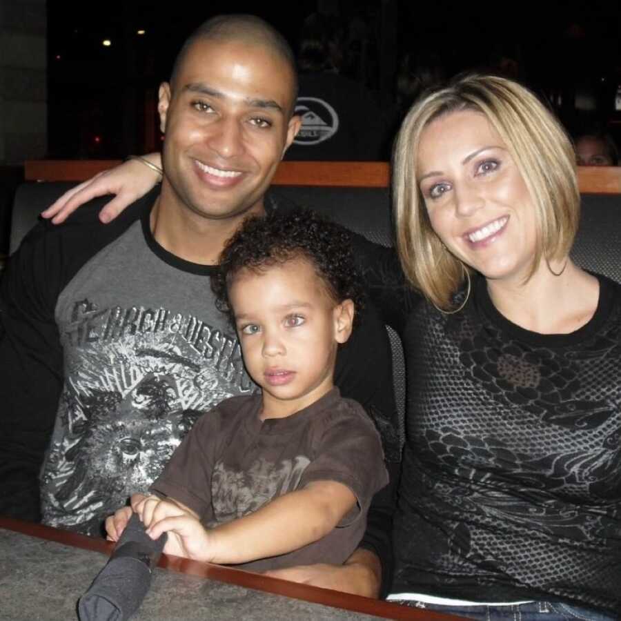 Interracial married couple take a photo out at a restaurant with their special needs son who has Fragile X Syndrome