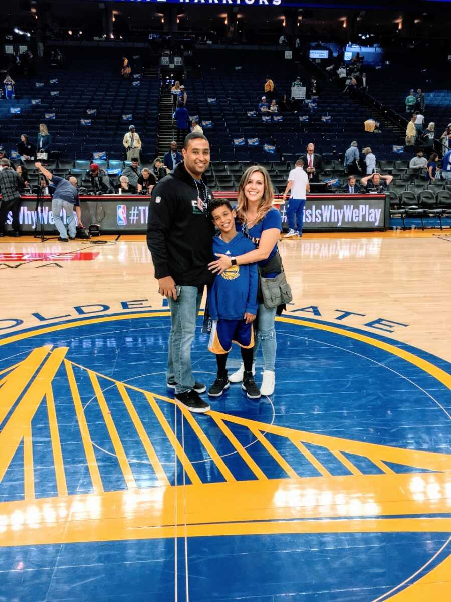 Couple take a photo with their son who has Fragile X Syndrome in the middle of a basketball court