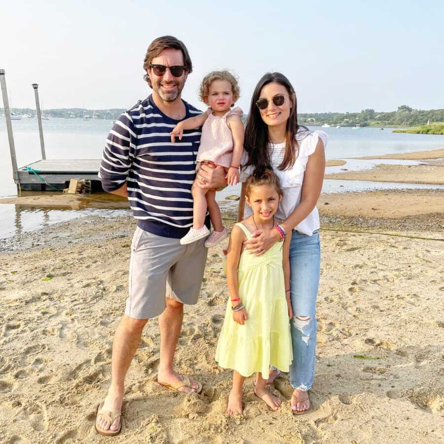 Family of four take a photo together while enjoying some vacation time out at the beach