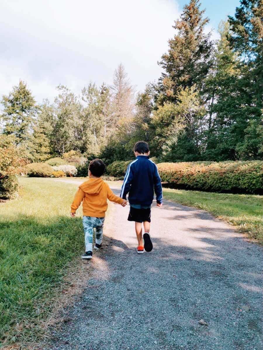 Mom snaps a photo of her two sons walking hand-in-hand during a nature walk