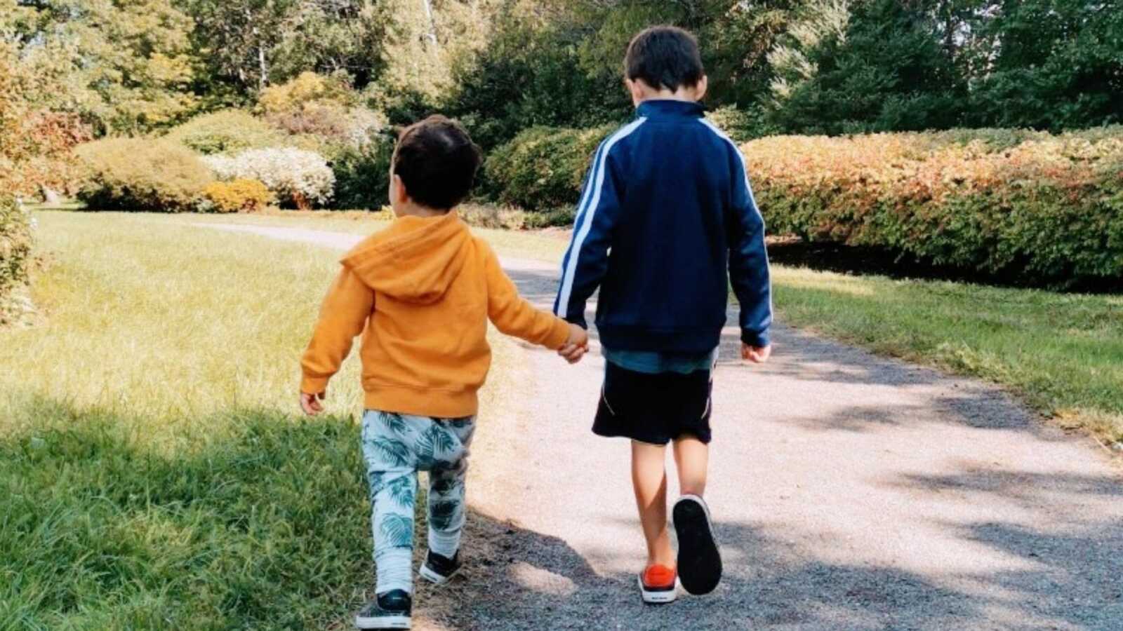 Boy mom takes a photo of her sensitive sons holding each other's hands during a walk