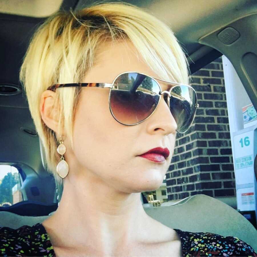 Working mom of 3 boys takes a serious selfie in the car, all primped and ready for work, while stopping at a gas station to fill up