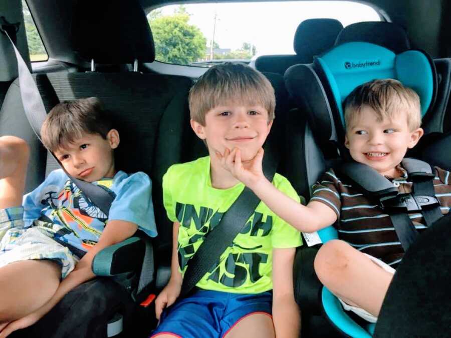 Mom snaps a photo of her three sons smiling in the backseat of her car while on the way to school one morning