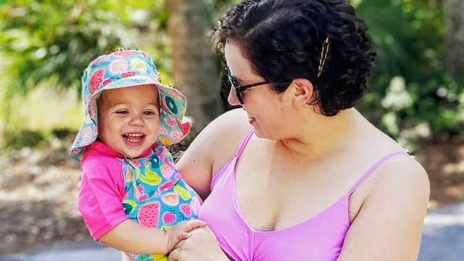 Mom and daughter enjoy the day out in the sun together, both wearing bathing suits