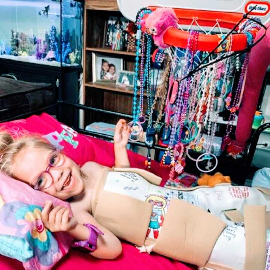 Little girl recovering from tendon lengthening surgery smiles while in a full body splint