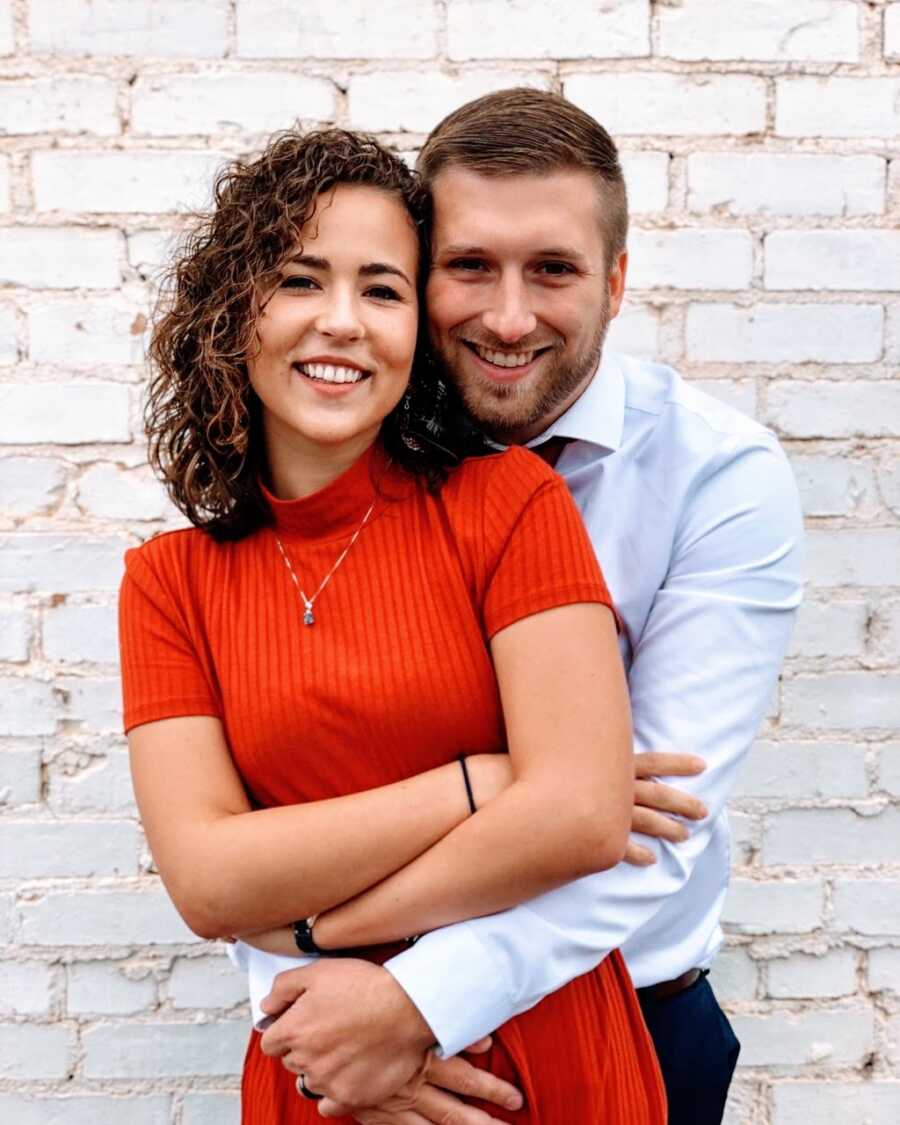 Young engaged couple smile candidly for a photo while embracing