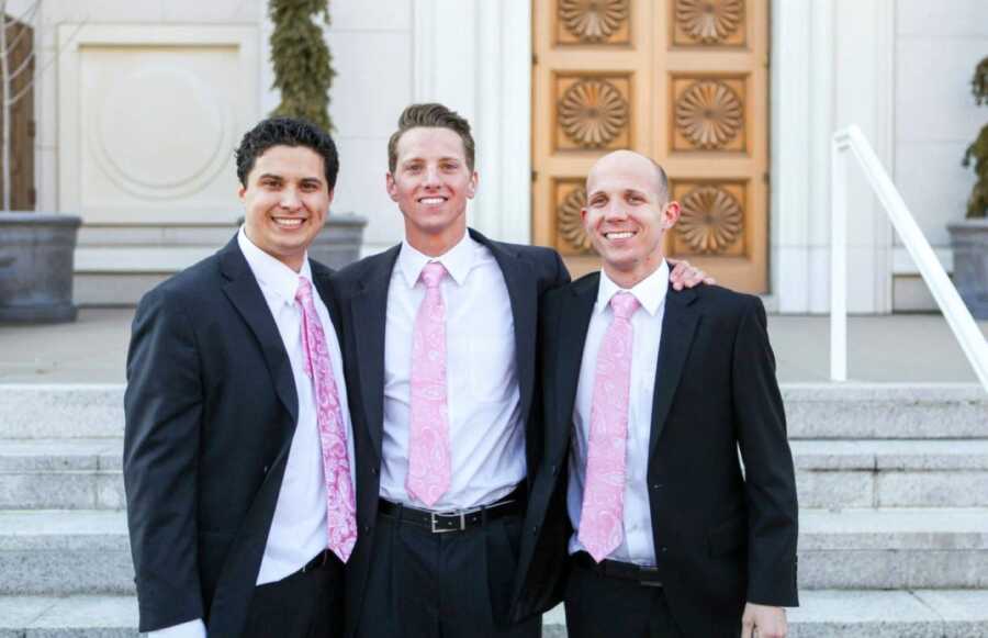 Three brothers all adopted by the same family take a photo together at one of their weddings