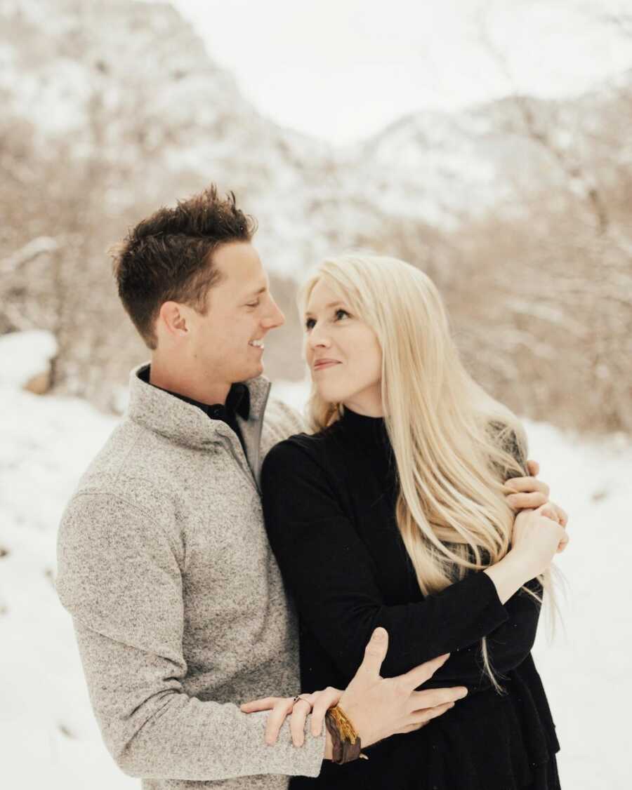 Young married couple take a romantic and intimate photo together, staring into each other's eyes as snow falls down around them