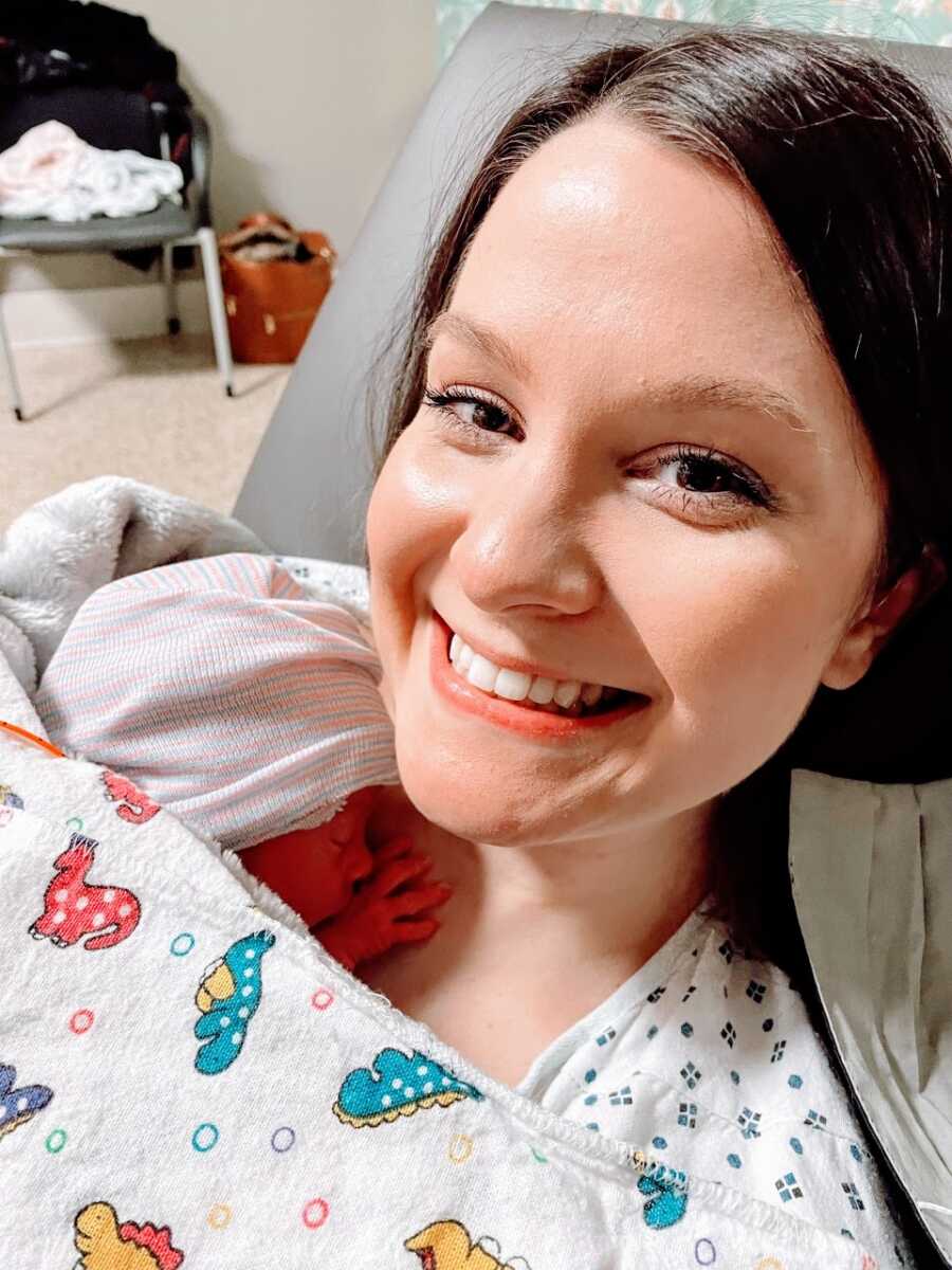 New mom smiles big while she holds her premature newborn daughter for the first time