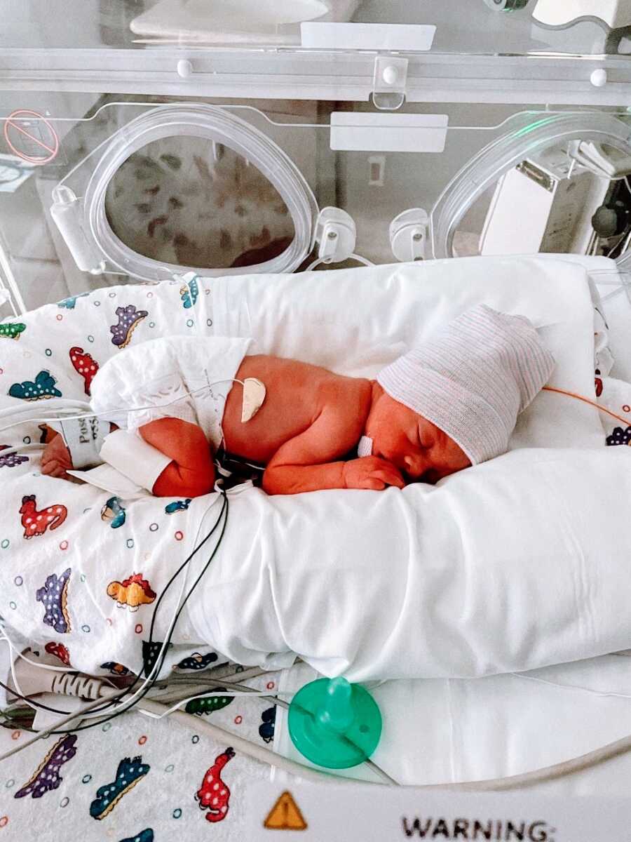 First time parents snap a photo of their newborn daughter sleeping in an isolette in the NICU
