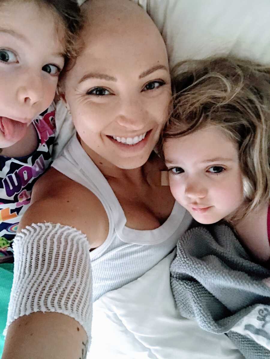 Mom of two battling breast cancer takes a silly selfies with her daughters while they all cuddle in bed together