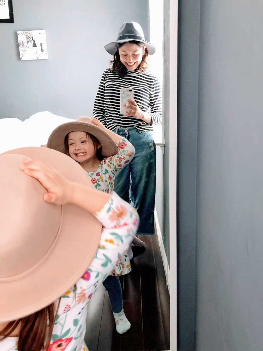 Girl mom of two takes a mirror selfie with her daughter with Down Syndrome