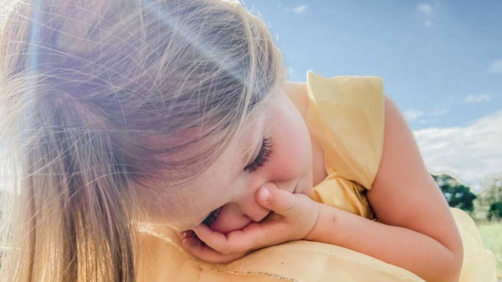 Little girl in a yellow dress crouches on the ground while experiencing anxiety during a walk