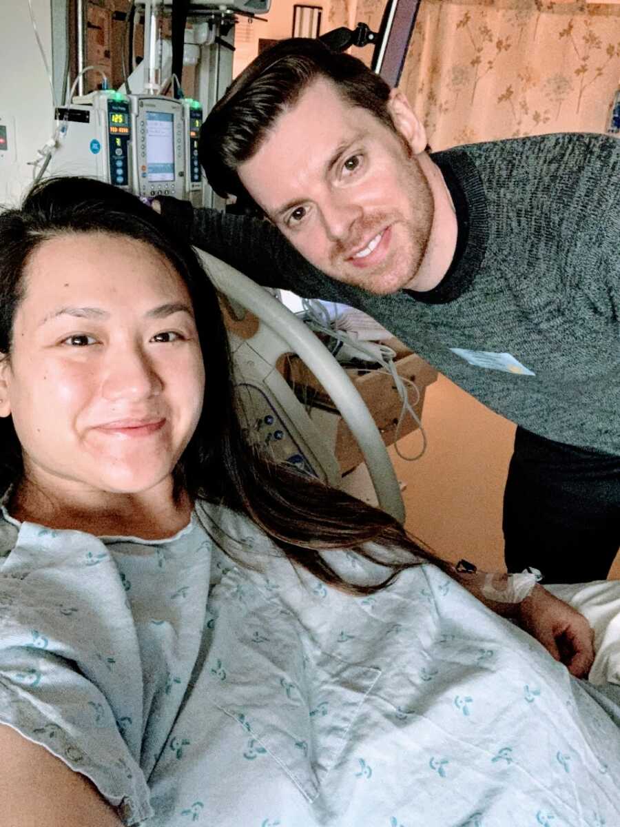 Heavily pregnant woman getting ready to go into labor takes a selfie with her husband at the hospital