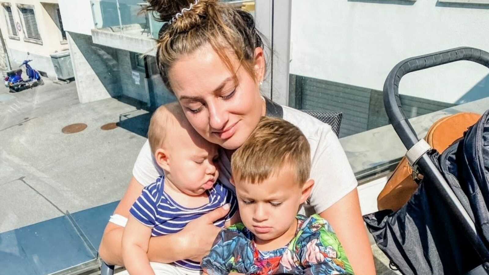 Mom cuddles her sons in the warm sun of Switzerland while on vacation