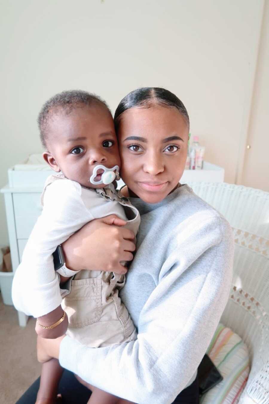 Young solo mom and son take a serious selfie together, showing off how much they look alike, while spending time in his nursery