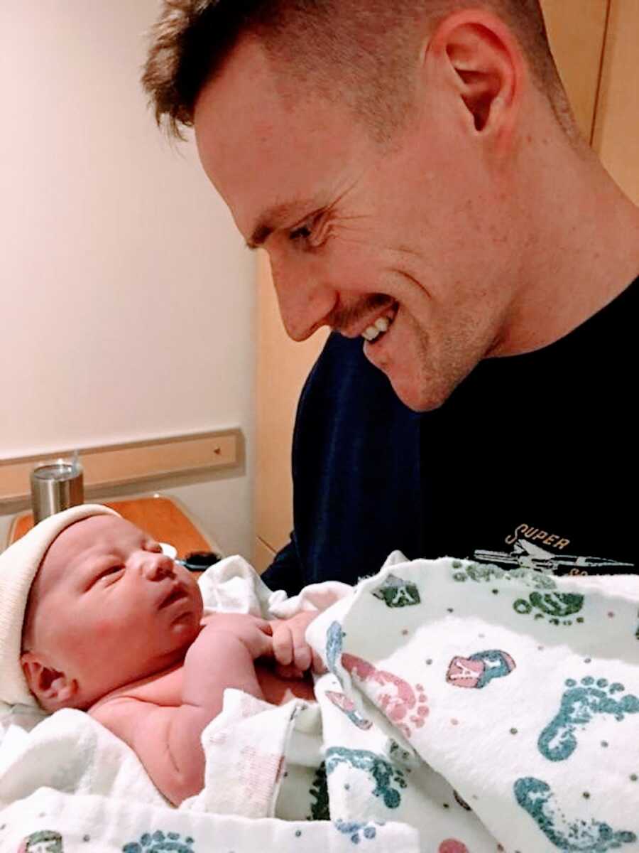 sober man smiles at newborn son