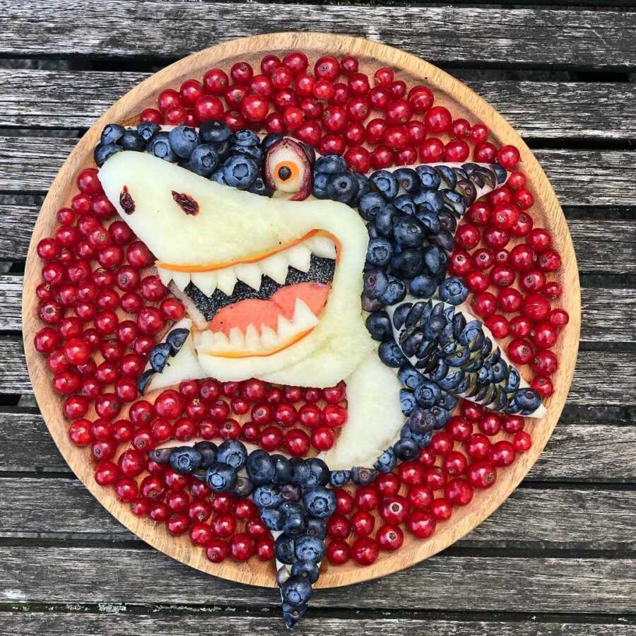 Edible food art fruit platter scene of a cartoon shark. 