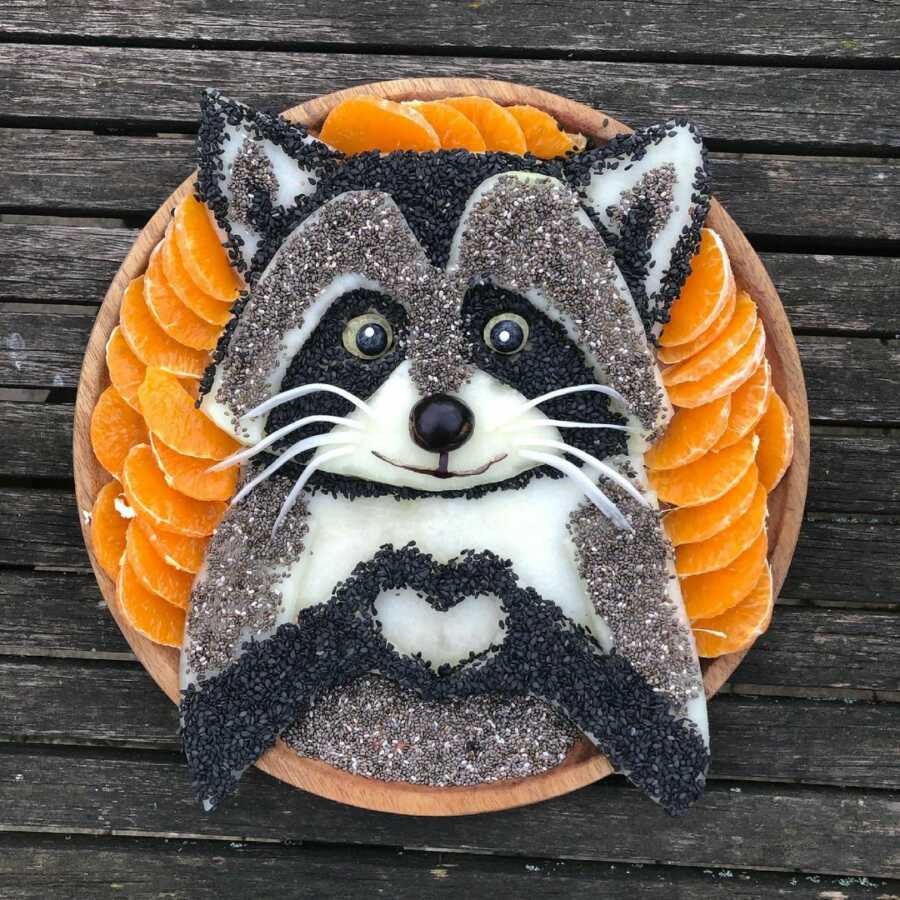 Edible food art fruit platter scene of a racoon. 