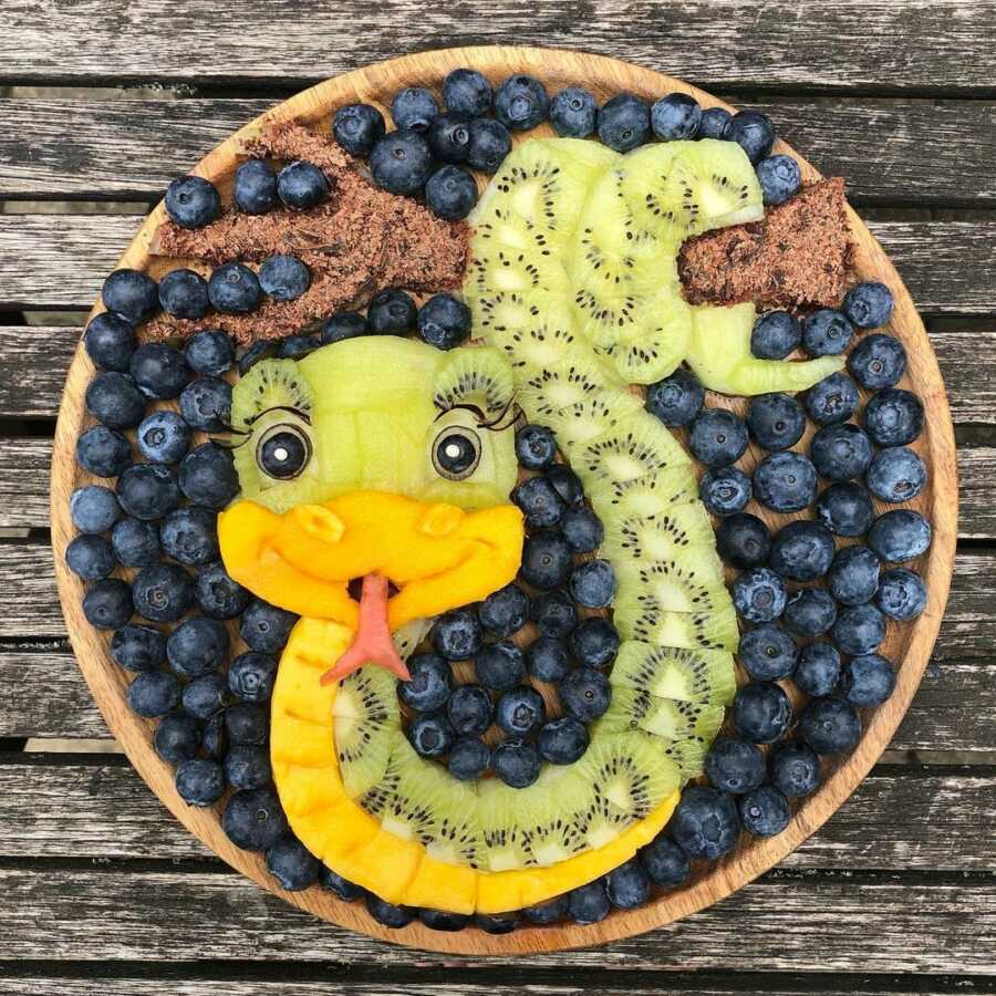 Edible food art fruit platter scene of a cartoon snake. 