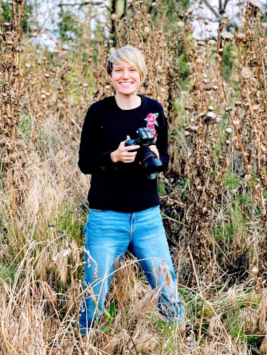 Woman holds camera out in field